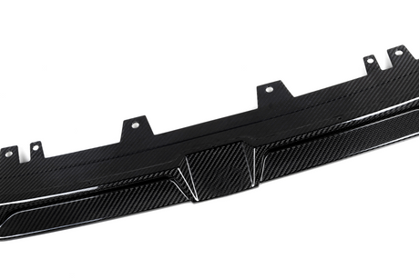 A carbon fiber car diffuser lies flat, showing textured pattern and mounting brackets, set against a plain white background.