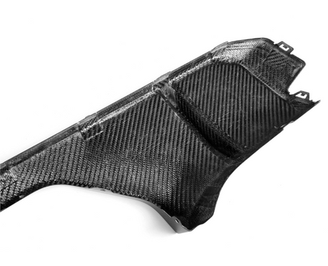 A carbon fiber panel lies against a plain white background, showcasing its textured, woven surface and angular shape, suitable for use in high-performance automotive or aerospace applications.