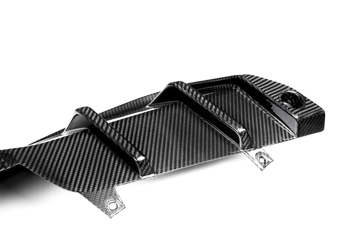 Carbon fiber car part with raised fins, resting on a white surface, featuring a glossy, patterned design and mounting holes.