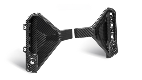 Two black carbon fiber car parts with angular designs are positioned facing each other. The left piece has visible attachment points; the right features an array of cutouts.