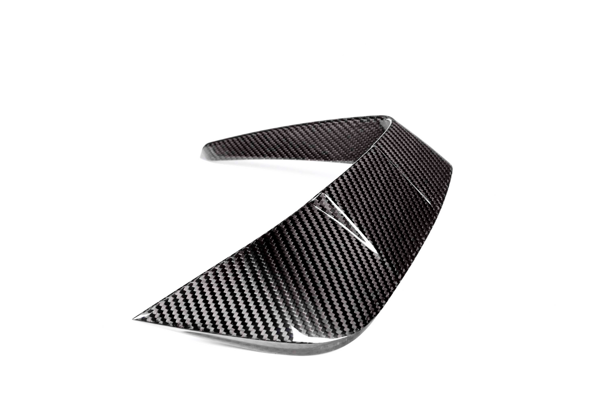A carbon fiber car spoiler curves upward, designed for aerodynamic enhancement, displayed against a white background.