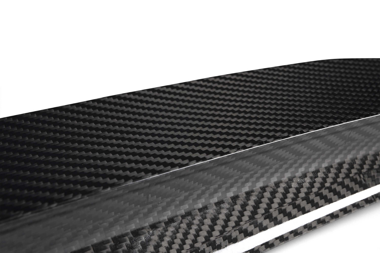 A close-up view of a glossy carbon fiber texture, displaying its distinctive woven pattern. The material appears sleek and polished, set against a plain, light background.