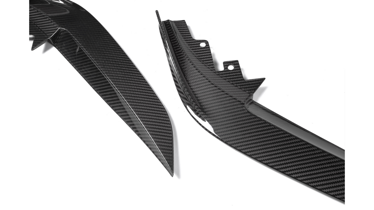 Two carbon fiber car body parts lie on a white surface, showcasing sleek, angular designs and the distinctive checkered pattern typical of carbon fiber material.