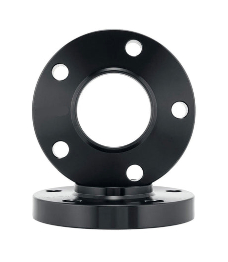 A black metal flange with five bolt holes rests vertically on another similar flange, both situated against a white background.
