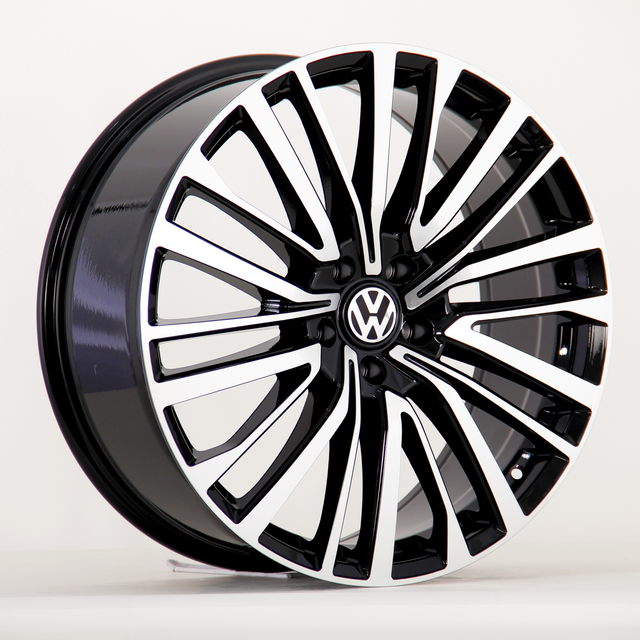A car wheel features a black and silver multi-spoke design with a central Volkswagen emblem, displayed against a plain white background.