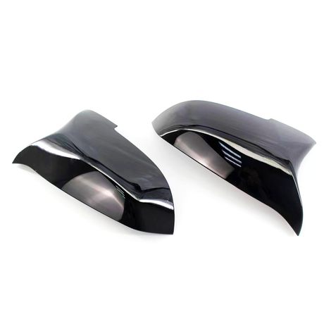 Black, glossy car mirror covers are shown lying side by side on a white background, reflecting light and their smooth, curved design.