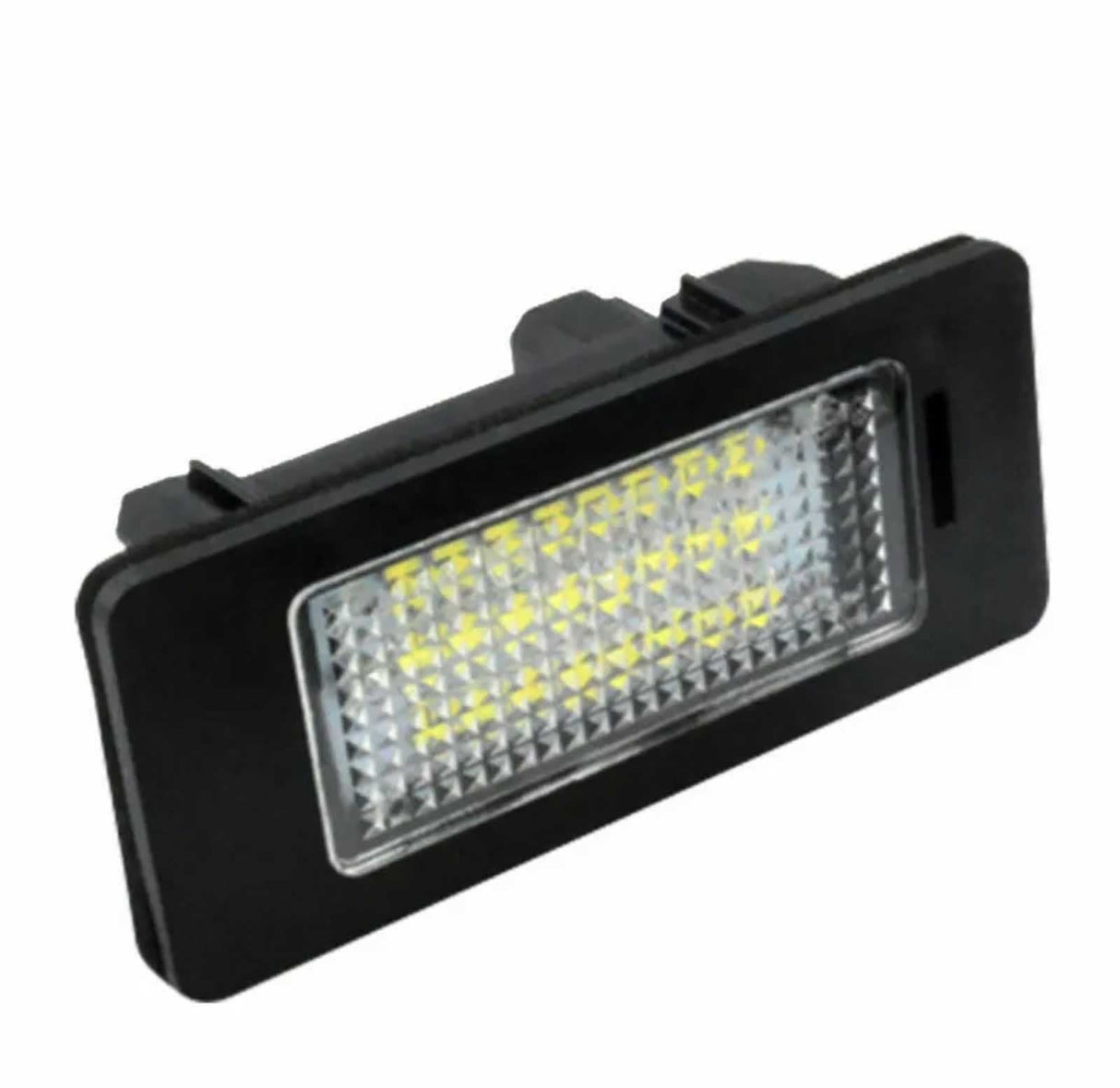 A rectangular LED light with a black frame and clear lens, displaying multiple yellow light diodes, lies at an angle on a plain white background.