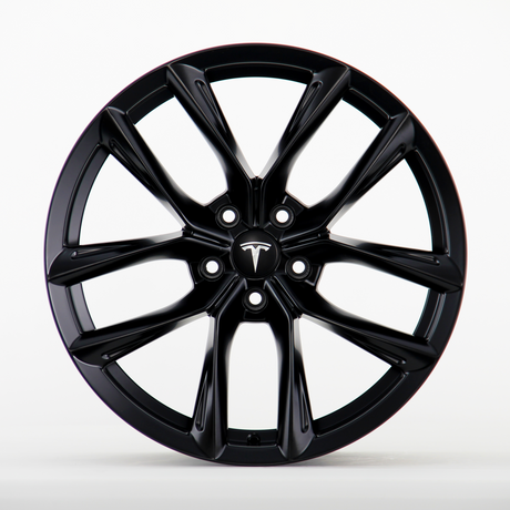 A black wheel rim featuring a sleek, multi-spoke design with the Tesla logo visible at the center, placed against a plain white background.