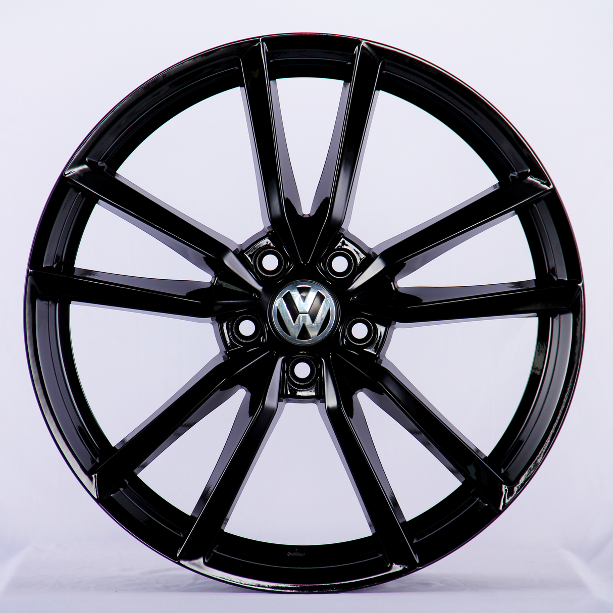 A black alloy car wheel is displayed with a five-spoke design, featuring the Volkswagen logo in the center, set against a plain white background.