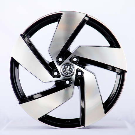 A metallic car wheel with a five-spoke design featuring a central logo; it rests against a plain white background.