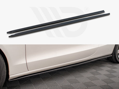 Two long, narrow black side skirt extensions displayed above the side profile of a white car. The car is parked on a textured floor, enhancing its sporty appearance.