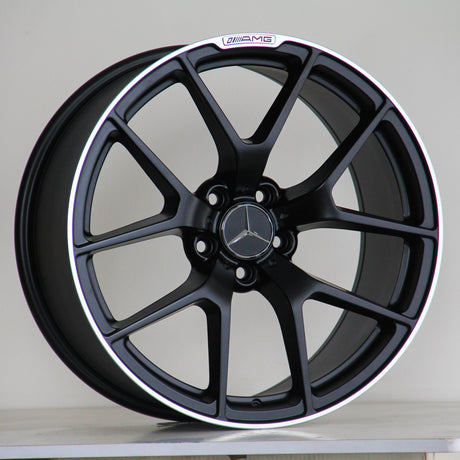 A black alloy wheel with a silver Mercedes logo, features the text "AMG" above the rim. It rests on a light surface against a plain background.
