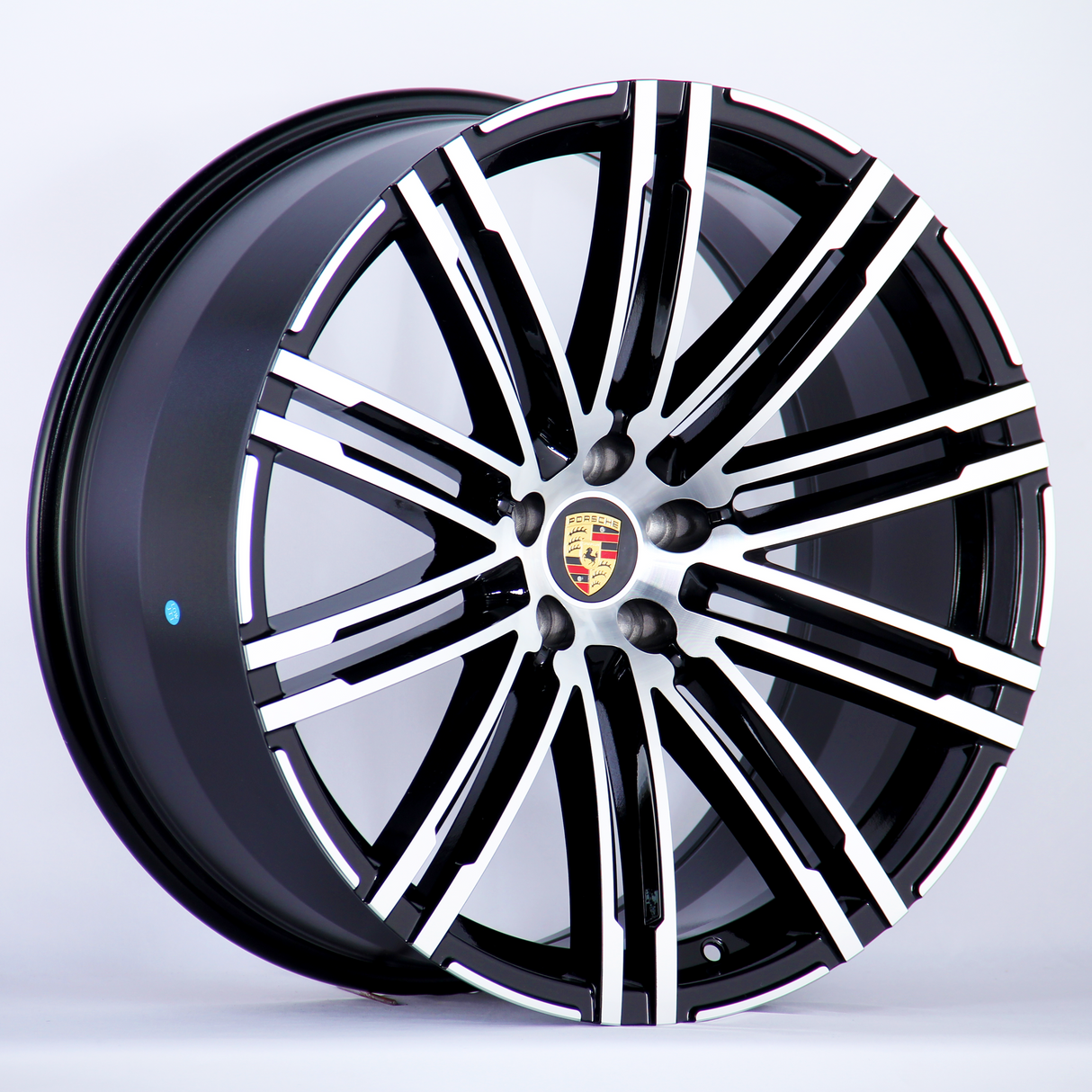 A black and silver alloy wheel with a multi-spoke design featuring the Porsche logo at the center, displayed against a plain white background.