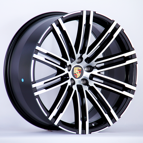 A black and silver alloy wheel with a multi-spoke design featuring the Porsche logo at the center, displayed against a plain white background.