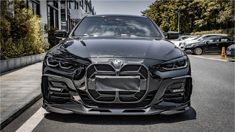 A sleek black car is parked on the side of a street, with modern headlights and a distinctive front grille. Buildings and parked cars line the background.