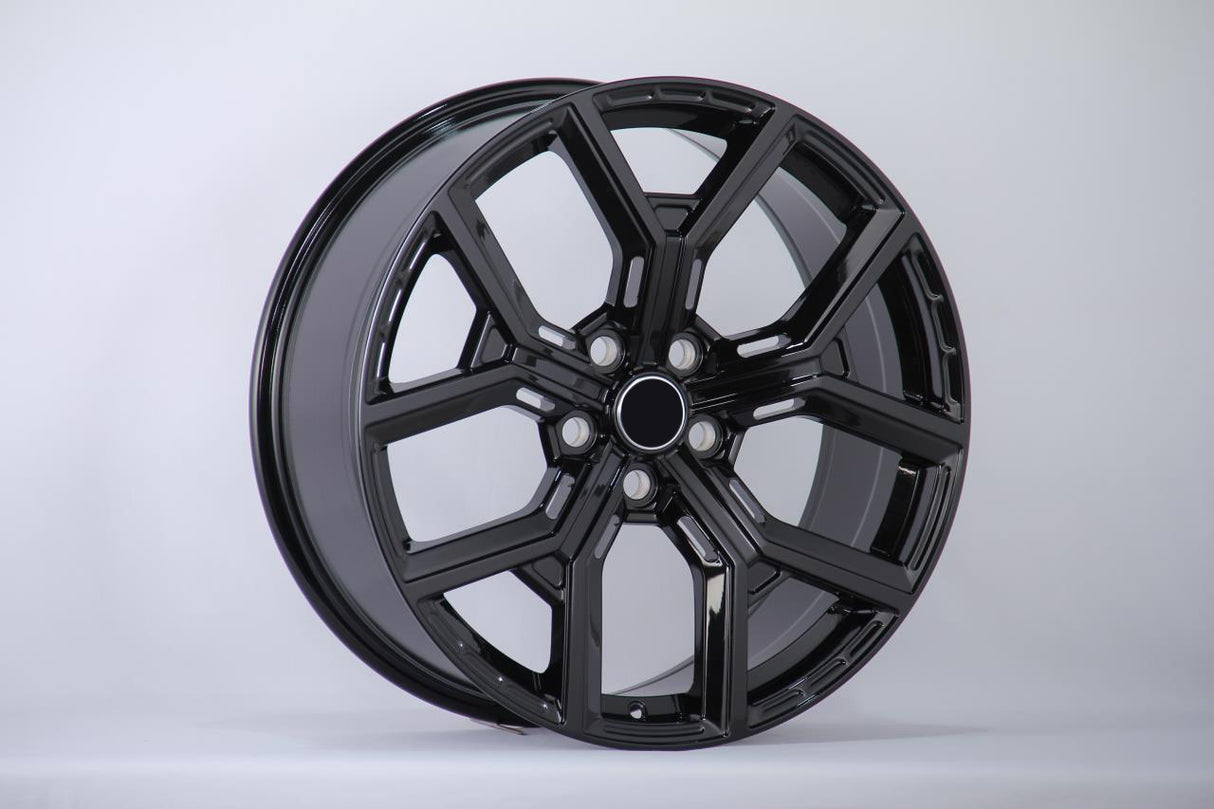 A glossy black alloy wheel with a multi-spoke design is displayed upright against a plain white background, showcasing its smooth and polished surface.