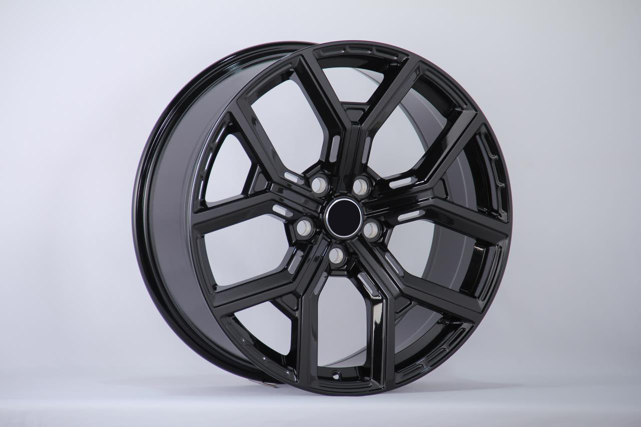 A glossy black alloy wheel with a multi-spoke design is displayed upright against a plain white background, showcasing its smooth and polished surface.