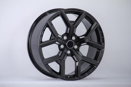 A glossy black alloy wheel with a multi-spoke design is displayed upright against a plain white background, showcasing its smooth and polished surface.