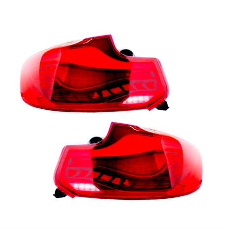 Two red car taillights are displayed side by side on a white background, showcasing their curved design and internal light bulb structure, indicating automotive components.