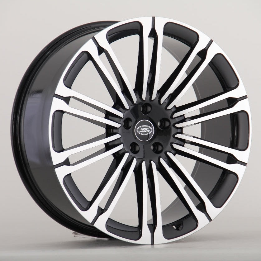 A black and silver Land Rover alloy wheel with multiple spokes is displayed against a plain gray background. The center cap features the "LAND ROVER" logo in white text.