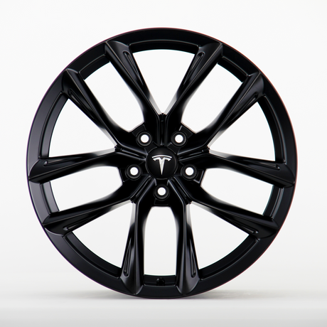 A black Tesla wheel rim with a sleek, multi-spoke design is shown in a clean, white studio setting. The central hub cap features the Tesla logo prominently.
