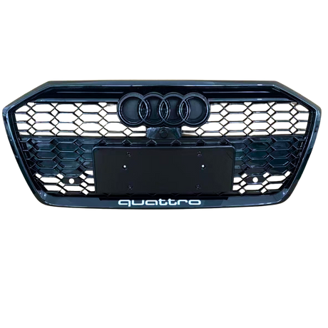 A front car grille displays the Audi logo with four rings and a honeycomb pattern. Below, "quattro" text is located. The background is plain, emphasizing the grille design.