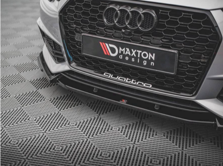 A car's front grille, featuring the Audi logo and honeycomb pattern, rests on a geometric-patterned floor. Text reads "MAXTON design" and "quattro" on the lower bumper.