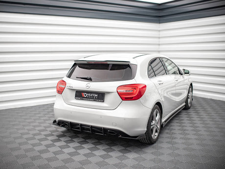 A white Mercedes-Benz A 180 d is parked in a modern, bright showroom with textured gray flooring and a striped white wall. A rear license plate reads "Maxton design."