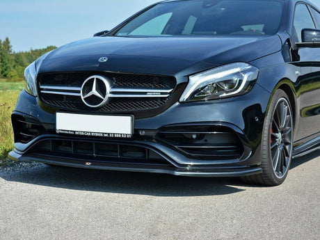 A black Mercedes-Benz car is parked on a road, showcasing its sleek front grille and headlights. Text: "Mercedes-Benz INTER-CAR RYBNIK tel. 32 888 53 01." Grassy fields are in the background.