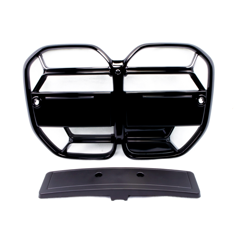 A black, glossy vehicle grille with a geometric pattern lays flat, accompanied by a separate rectangular piece below it, on a plain white background.