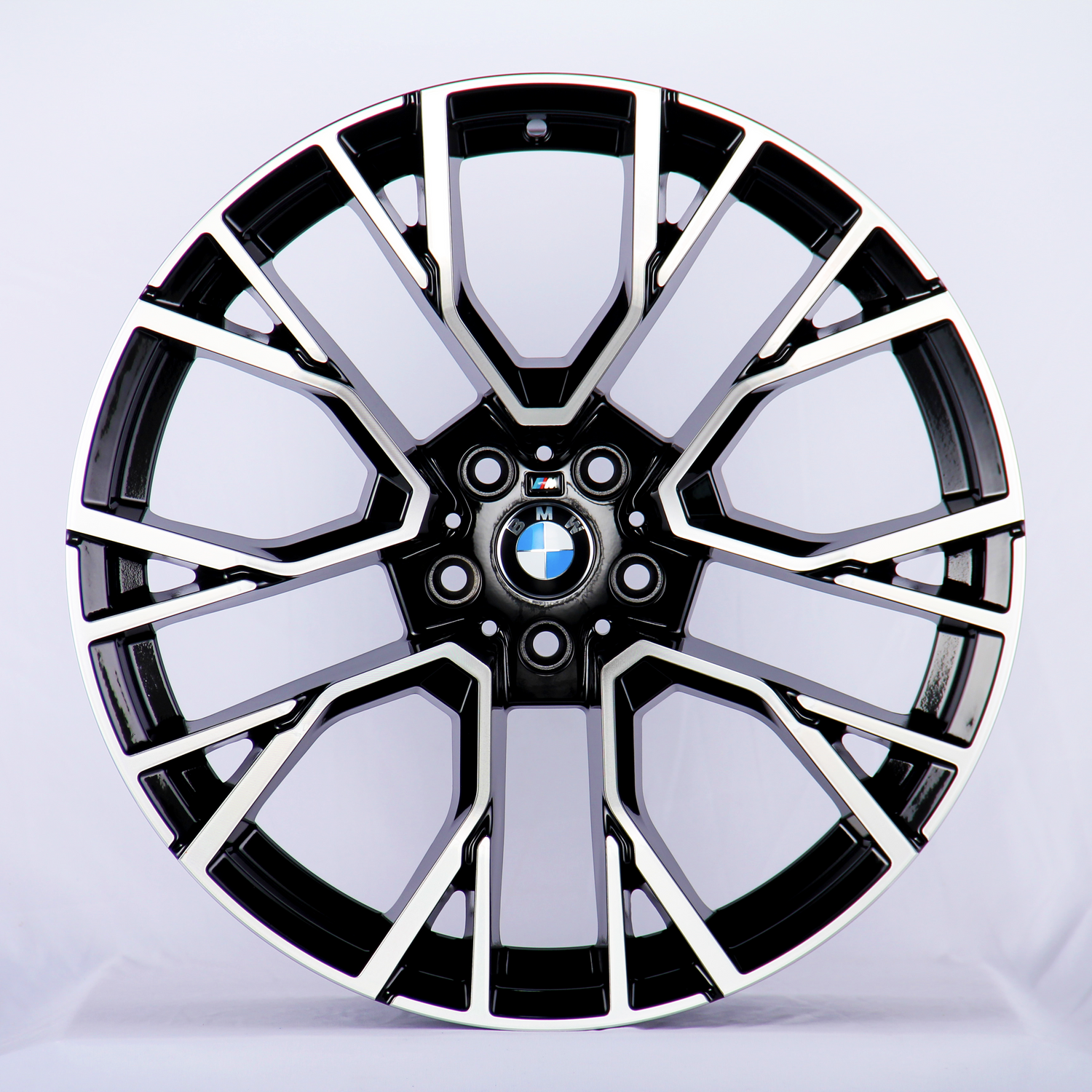 A black and chrome car wheel rim, with intricate geometric patterns, displaying the BMW logo at its center; set against a plain white background.
