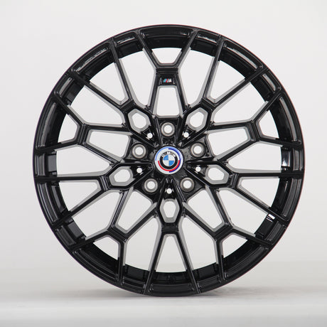 A glossy black, intricately designed car wheel with a central BMW logo and "M" insignia, set against a plain white background.