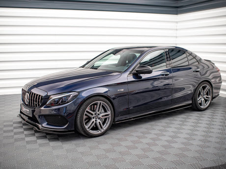 A dark blue sedan, parked on patterned flooring, features sleek design and five-spoke alloy wheels. The backdrop consists of angled, white metal walls with a modern, industrial style.