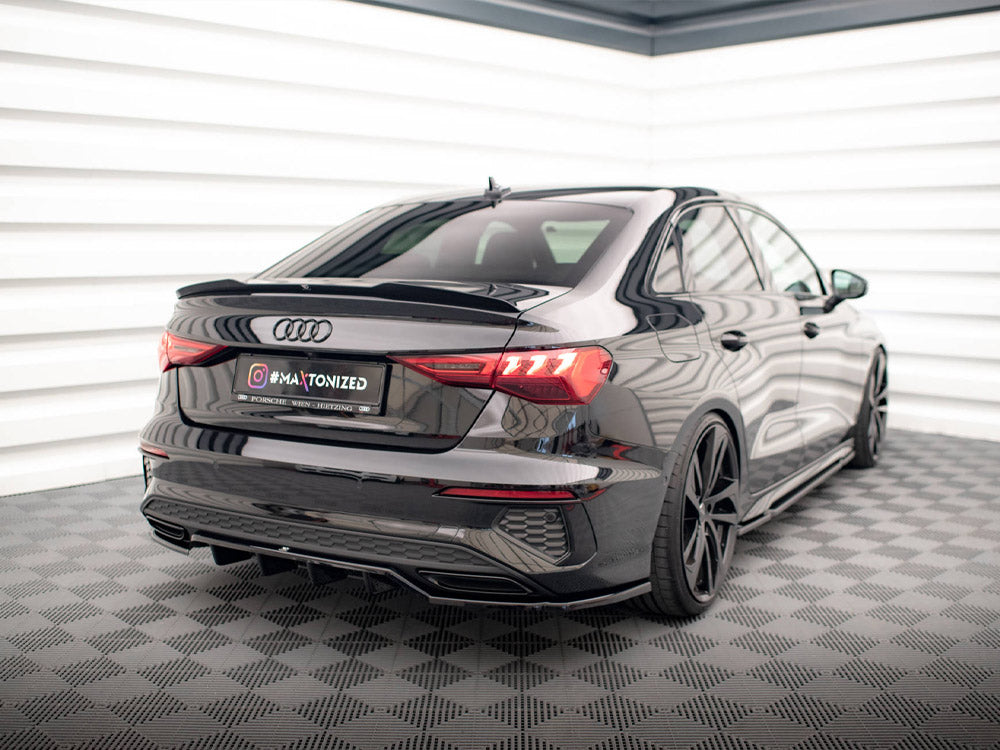 A black Audi car is parked in a well-lit showroom with checkered flooring. The license plate reads "@MAXTONIZED."