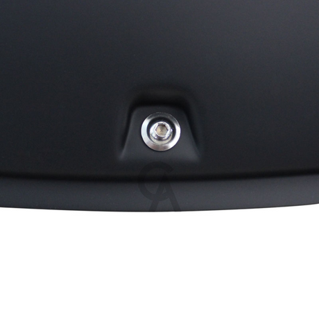 A metallic screw is securely embedded in a smooth, matte black surface. The setting appears industrial, suggesting it may be part of equipment or machinery.