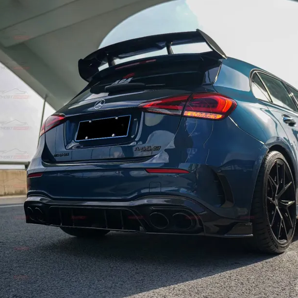 A dark blue Mercedes-AMG A35 car is parked, highlighting its aggressive rear spoiler and quad exhausts. It is positioned under a modern, curved architectural structure.