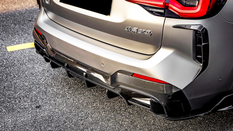 Car rear with a carbon fiber diffuser, parked on asphalt. "华晨宝马" text on the back, red taillights illuminated, set in bright daylight.