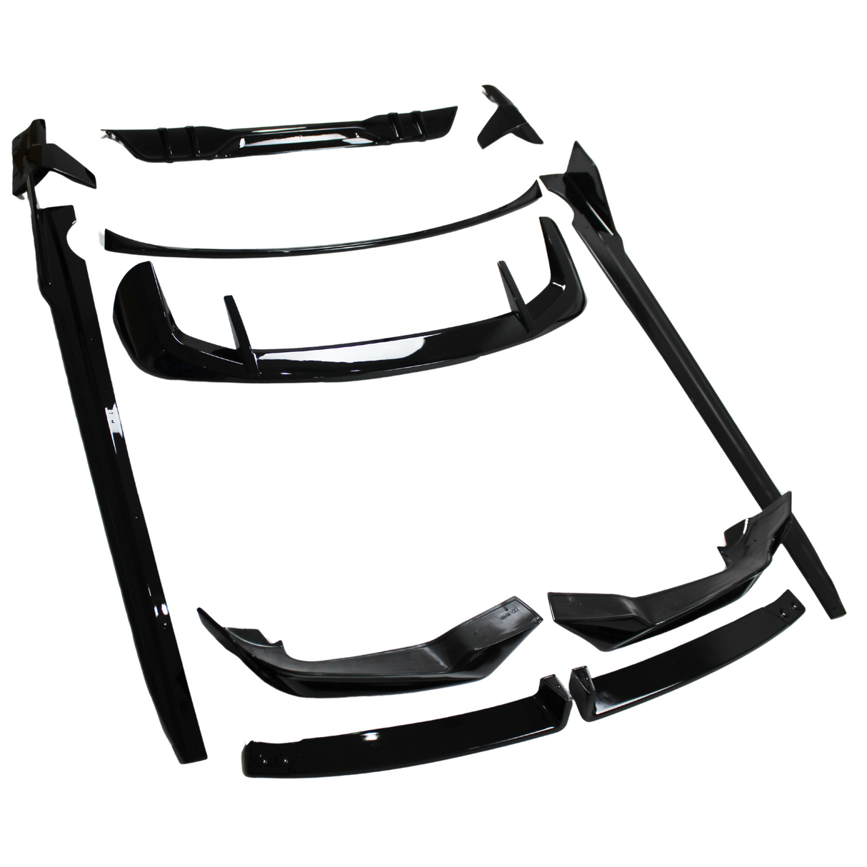 Black automotive body kit parts laid out on a white surface; several pieces include spoilers, skirts, and bumpers, all designed for vehicle modification.
