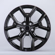 Black, glossy, multi-spoke alloy wheel; resting upright in a well-lit studio setting; casting a slight shadow on the white background.