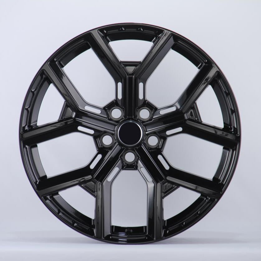 Black, glossy, multi-spoke alloy wheel; resting upright in a well-lit studio setting; casting a slight shadow on the white background.