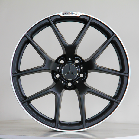 A black alloy wheel with a Mercedes-Benz logo is centered against a light background. It has a sleek multi-spoke design and displays the text "AMG" at the top.