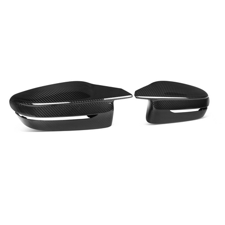 Two sleek, carbon fiber car mirror caps are lying side by side against a plain white backdrop, showcasing their glossy finish and aerodynamic design.