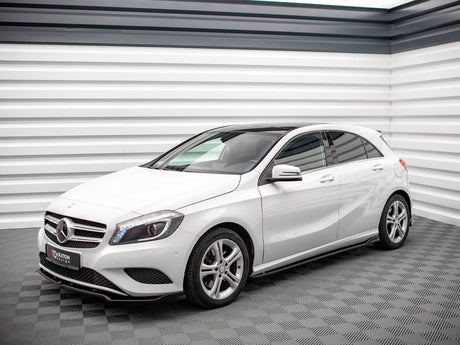 A white Mercedes-Benz hatchback is parked in a modern showroom with sleek, textured walls. A sign on the front reads "D'AXTON DESIGN."