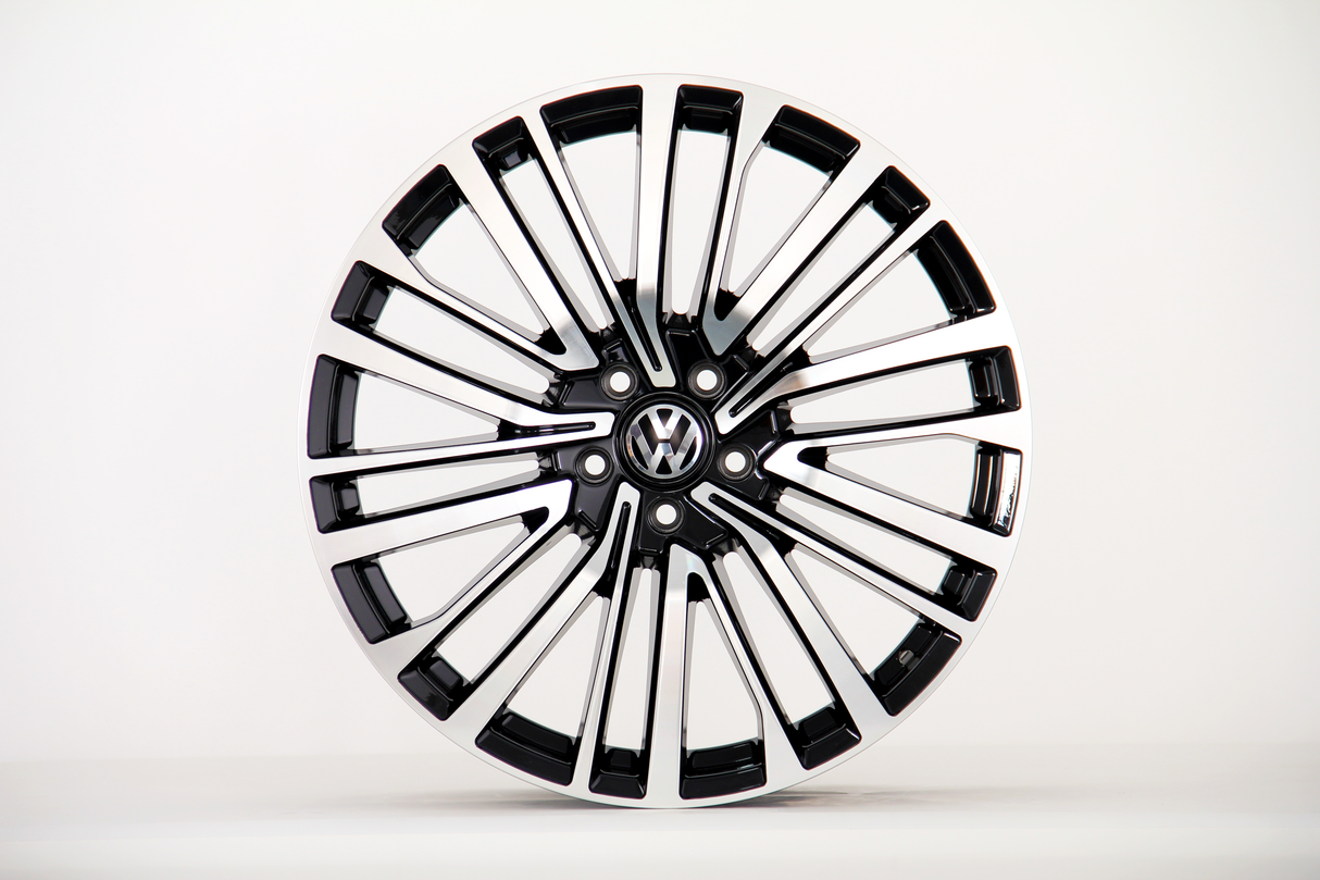 A polished alloy wheel with a modern, multi-spoke design, featuring a "VW" logo at the center, is displayed against a plain white background.