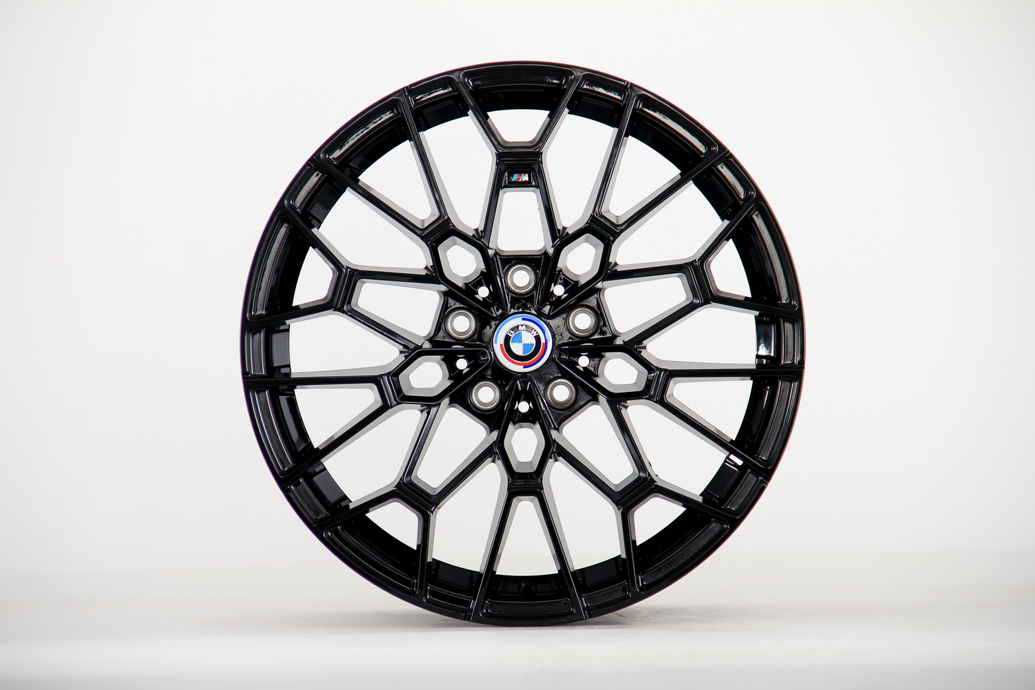 A black, geometric car wheel rim with a circular design featuring the BMW logo is displayed against a plain white background.
