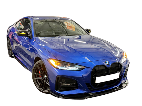 A blue sports car with headlights on is parked in a showroom, reflecting overhead lights. The environment's reflections highlight the vehicle's sleek, aerodynamic design.