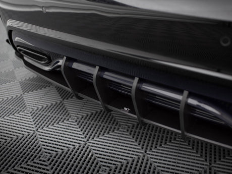 A sleek car diffuser with vertical slats at the rear, positioned above a textured, grid-patterned floor.
