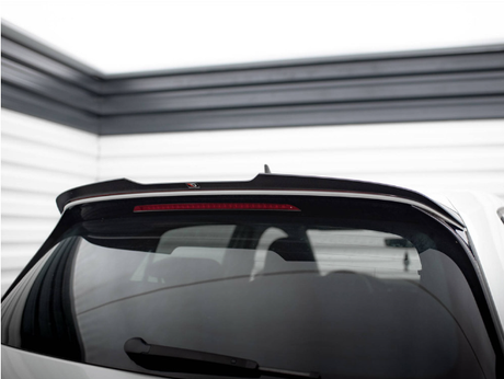 A car's rear window with a spoiler and brake light is parked in a garage. The walls are lined with horizontal white and black panels, creating a modern, enclosed space.