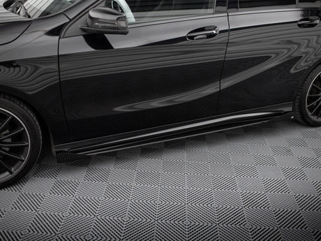 A black car is parked on a patterned surface, featuring prominent reflections and sleek, aerodynamic lines, with a visible side mirror and alloy wheels against a geometric background.
