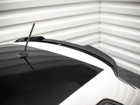 A car roof with a black roof spoiler and aerial, set in a corner with white horizontal wall panels.
